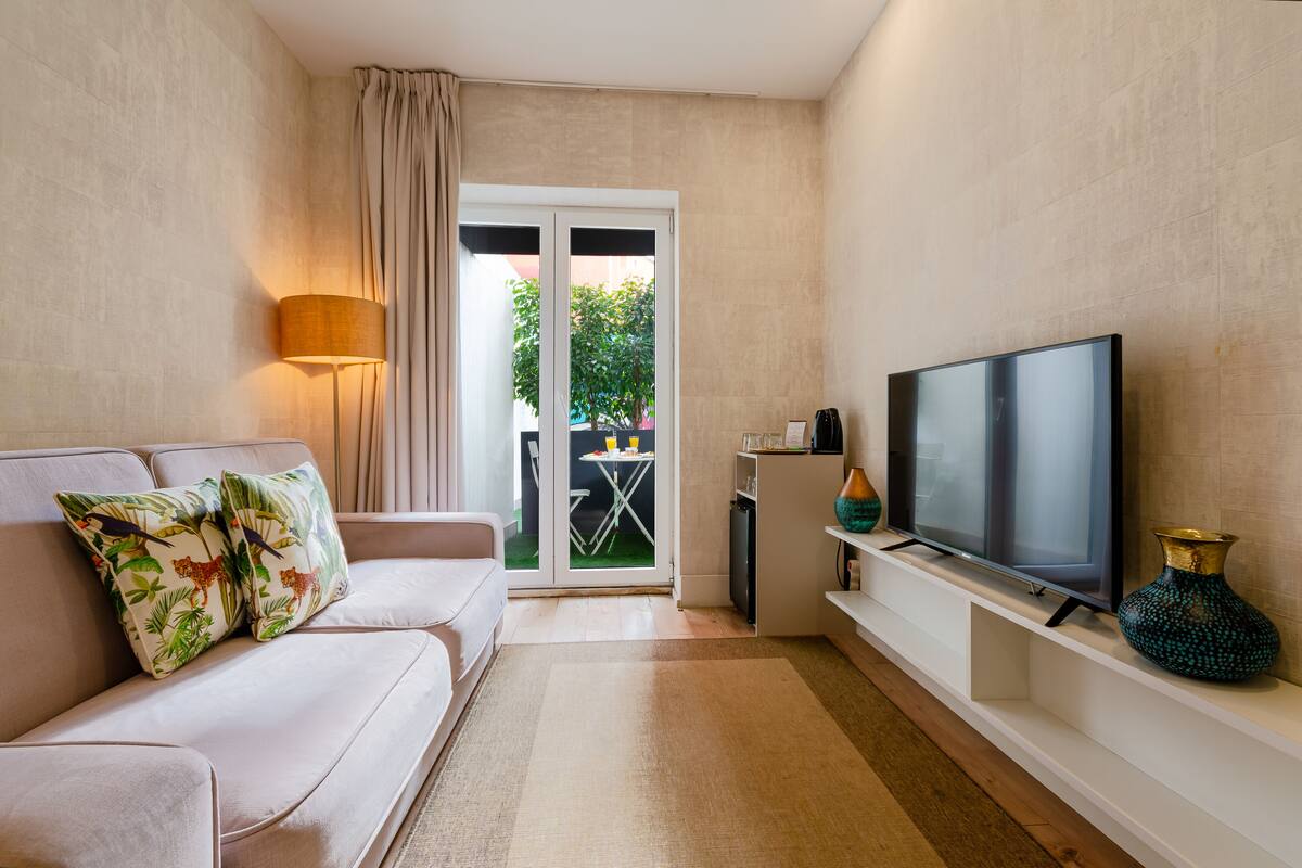 A living room with a sofa, TV, and a small table with a lamp.
