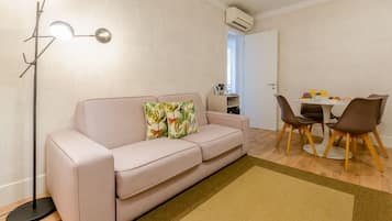 A modern living room with a sofa, a dining table with chairs, and a floor lamp.