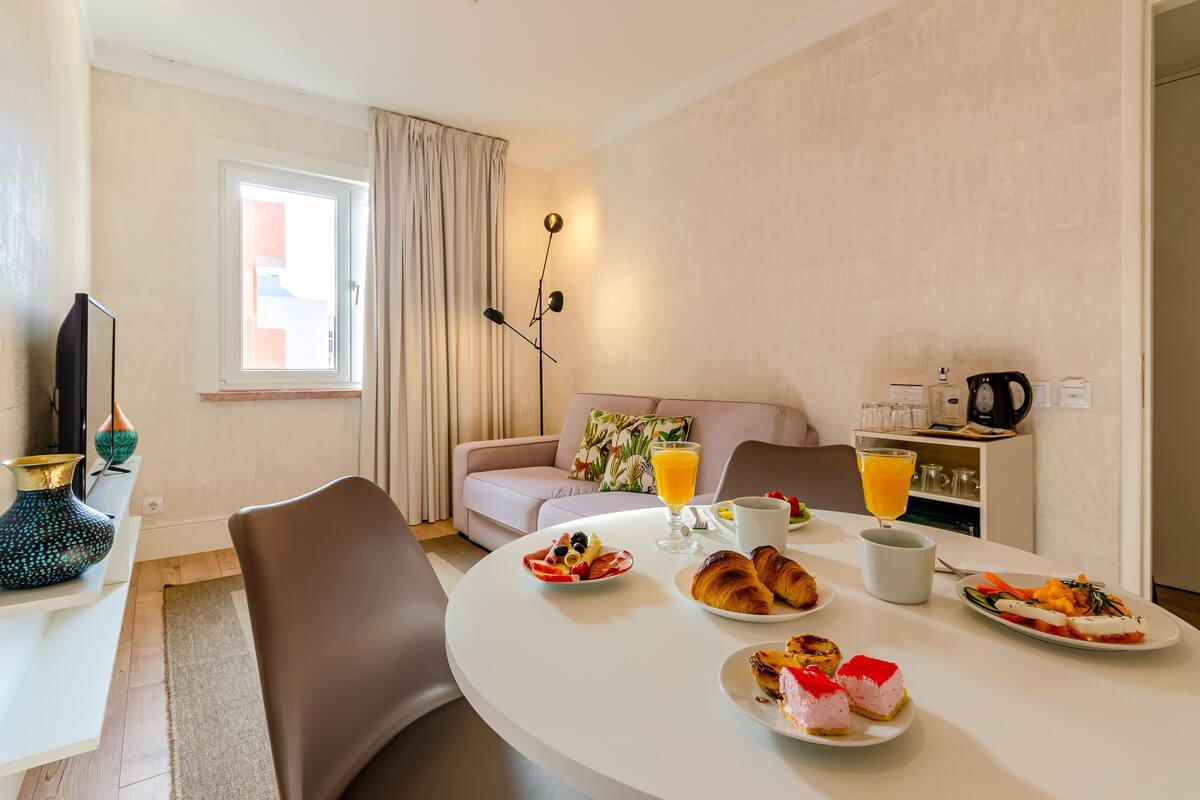 A dining area with a round table set for breakfast, including croissants, fruit, and juice.