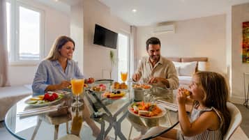 Un comedor moderno con una mesa de vidrio, platos para el desayuno y un televisor montado en la pared.