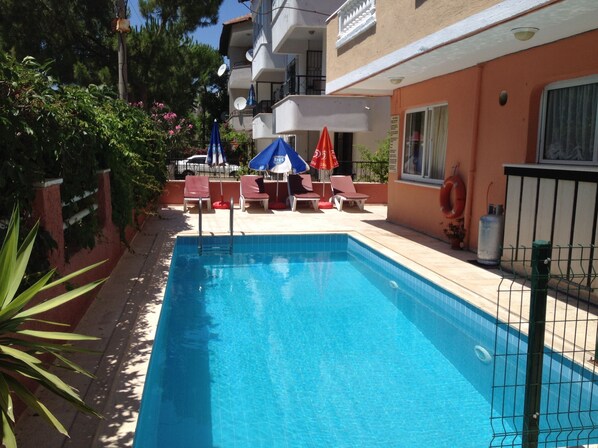 Una piscina al aire libre, sombrillas, tumbonas