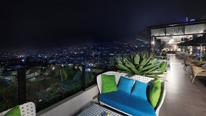 A rooftop terrace with a city view, outdoor seating, and a bar area. - Aston Inn Batu - Malang (Batu)