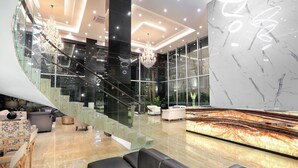 A modern lobby with a glass staircase, marble walls, and contemporary furniture. - Aston Inn Batu - Malang (Batu)