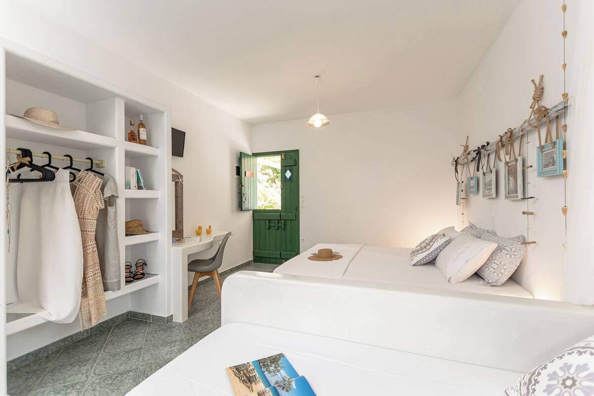 Ein kleines Zimmer mit einem Bett, einem Kleiderschrank, einem Schreibtisch und einer grünen Tür.