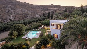 A modern villa with a swimming pool, surrounded by lush greenery and a hilly landscape. - Palatiana Agriturismo Philoxenia Cottages Retreat (Naxos)