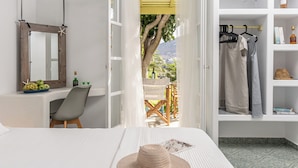 A bedroom with a bed, a chair, a desk with a mirror, a wardrobe, and a view of the outdoors. - Palatiana Agriturismo Philoxenia Cottages Retreat (Naxos)