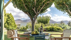 A patio with two chairs, a table with a book, a bottle, and a bowl of fruit. - Palatiana Agriturismo Philoxenia Cottages Retreat (Naxos)