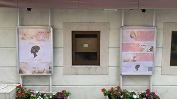 A building facade with two large posters advertising a beauty salon, a small window, and two flower planters.