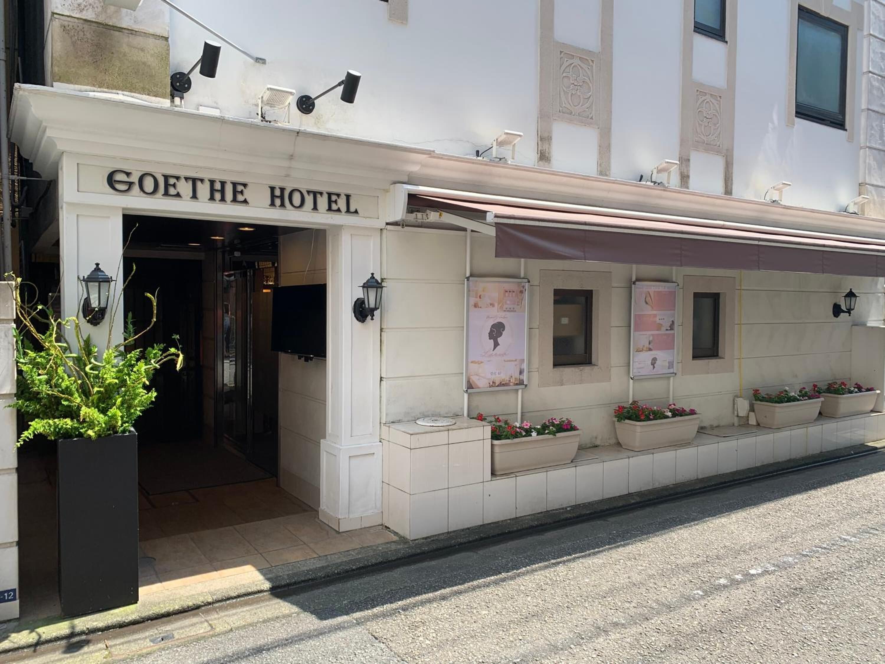 The exterior of Goethe Hotel with a classic facade, entrance, and flower planters along the side.
