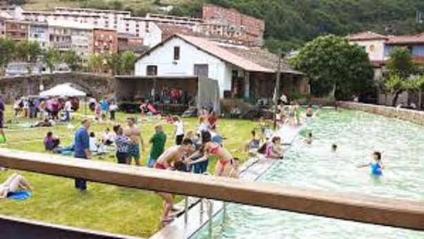 Une zone autour d’une piscine où des personnes nagent et prennent des bains de soleil.