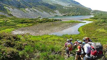 A group of hikers on a trail with a river and mountains in the background.