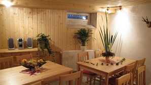 A wooden dining area with a table and chairs, a potted plant, and a mounted animal head on the wall. - Kammbaude Neuhermsdorf (Hermsdorf-Erzgebirge)