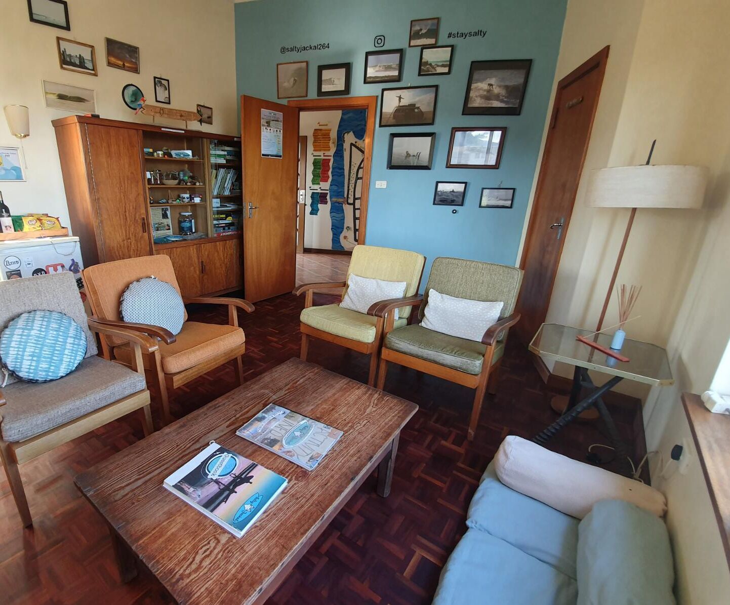 Un accogliente soggiorno con mobili in legno, un tavolino da caffè con riviste e una parete decorata con quadri.
