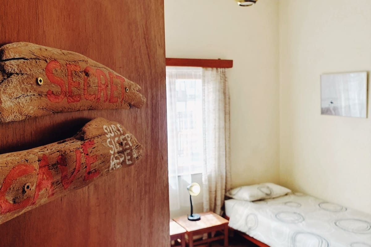 Ein Zimmer mit einem Bett, einem Schreibtisch und einem Holunderschild mit Text.