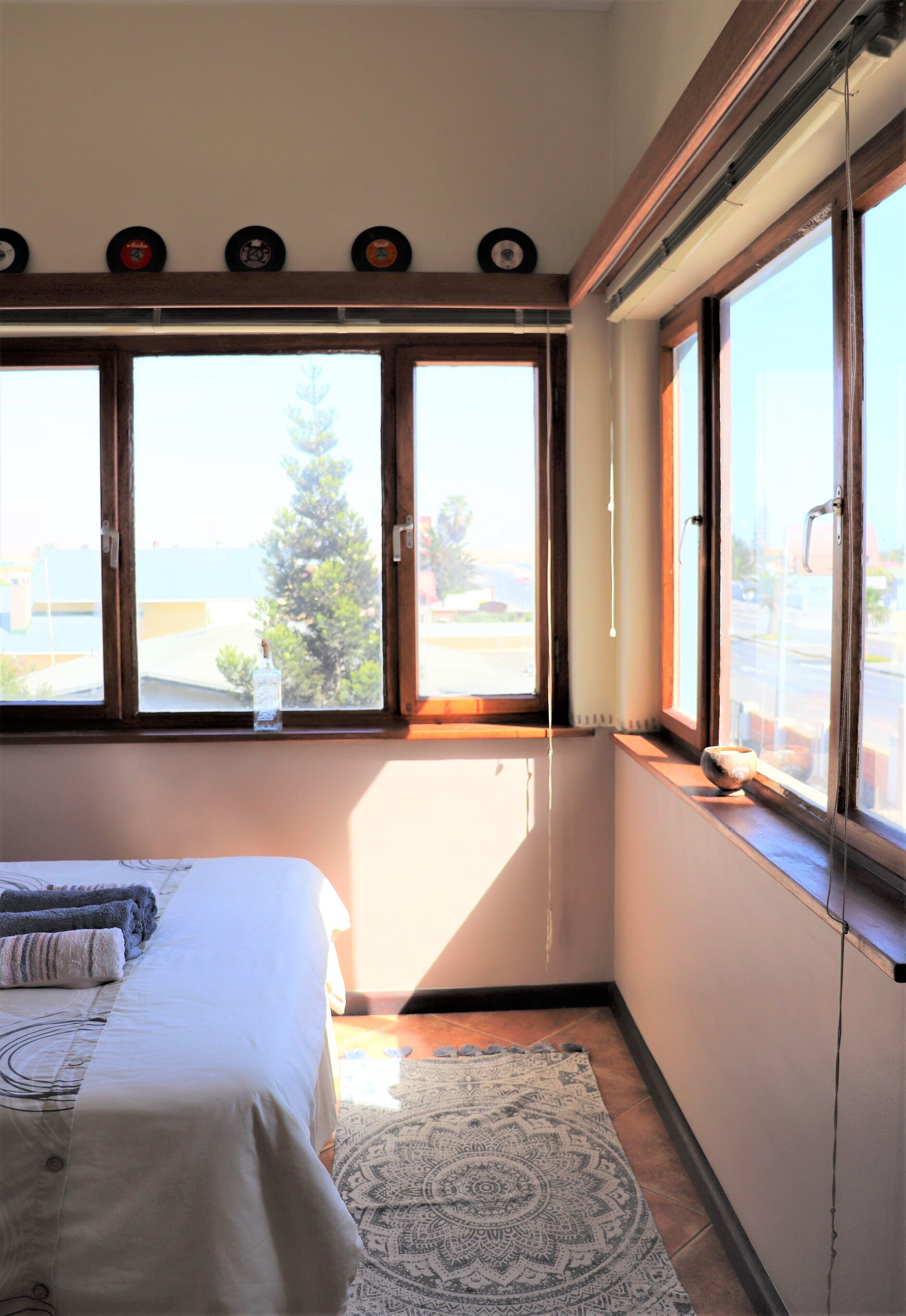 A bedroom with a bed, a window with a view of the outdoors, and a decorative wall with circular objects.