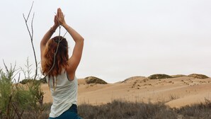 Una persona practicando yoga sobre una esterilla en un entorno natural al aire libre.