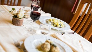 A dining table with plates of food, wine glasses, and cutlery. - Hotel Daniela (Levico Terme)