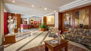 A spacious lobby with a marble floor, a statue, a sofa, and a coffee table. - Hotel Daniela (Levico Terme)