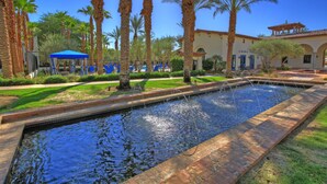 A pool area with palm trees, a covered seating area, and a building with arches. - Sensational Single Story Townhome Against the Mountains w/ garage, LQ121 (La Quinta)