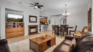 A spacious living room with a fireplace, a dining area, and a kitchen in the background. - Sensational Single Story Townhome Against the Mountains w/ garage, LQ121 (La Quinta)
