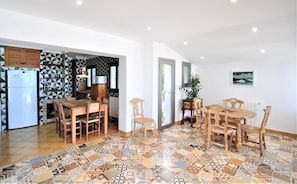 A spacious kitchen with a modern refrigerator, wooden cabinets, and a patterned backsplash.