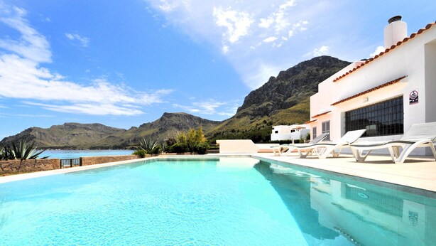 A swimming pool with lounge chairs and a mountain backdrop. - Villa XOROI- Dream front line Villa in Betlem (Mallorca) with pool and direct access to the sea. - Free Wifi (Artá)