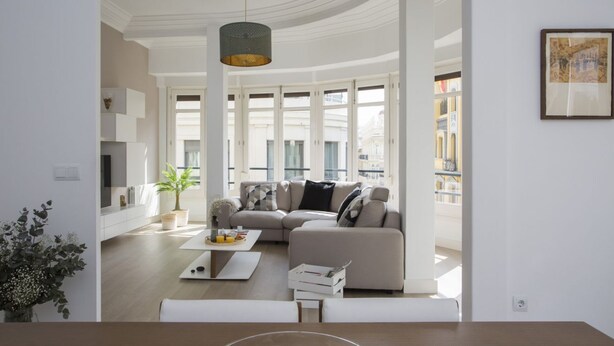 Ein modernes Wohnzimmer mit Ecksofa, Couchtisch und einer Topfpflanze.