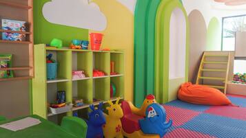 A children's playroom with colorful toys, a green bookshelf, and a blue elephant toy.