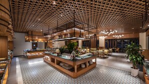 A modern hotel lobby with a patterned floor, a central island with tables and chairs, and a ceiling with a geometric design. - Dusit Princess Moonrise Beach Resort (Phu Quoc)