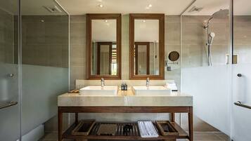 A modern bathroom with two sinks, a shower, and a vanity with a mirror.