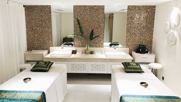 Relax in a stylish room with a double sink vanity, two single beds, and a cozy seating area.