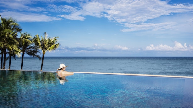 A clear blue pool with a view of the ocean and palm trees. - Dusit Princess Moonrise Beach Resort (Phu Quoc)