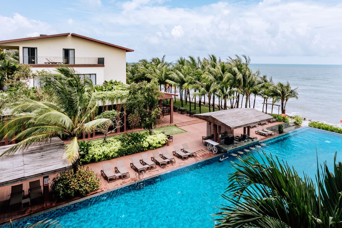 A resort with a swimming pool, lounge chairs, and a view of the ocean.
