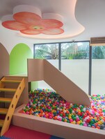 Un área de juegos con piscina de pelotas, un tobogán de madera y una escalera.