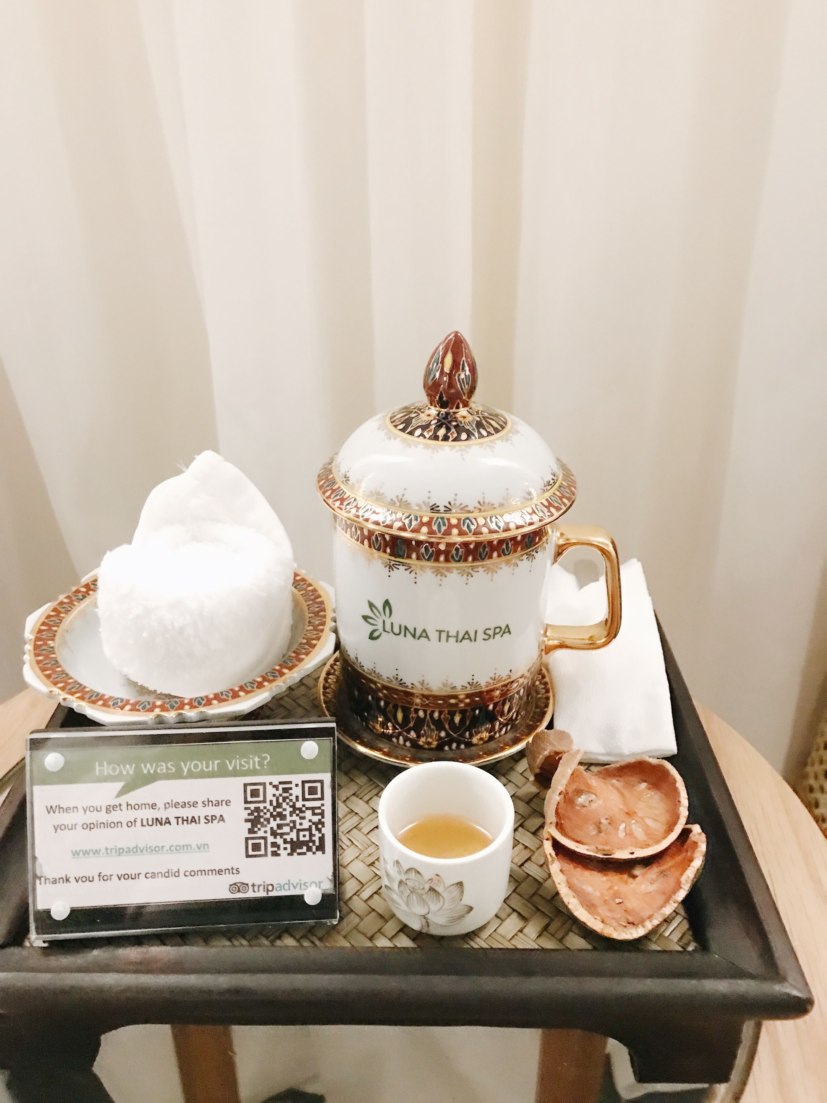 Ein Tablett mit einem weißen Teekessel mit der Aufschrift „LUNA THAI SPA“, einer Tasse Tee, einer Schüssel weißen Reis und zwei kleinen Tellern mit Speisen.