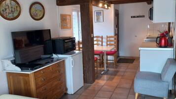 Une chambre confortable avec un lit, une télévision, une petite kitchenette et un coin repas.