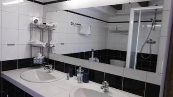 Een badkamer met twee wasbakken, een grote spiegel en een douche.