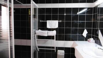Un baño con azulejos negros, un lavamanos blanco y un perchero para toallas.