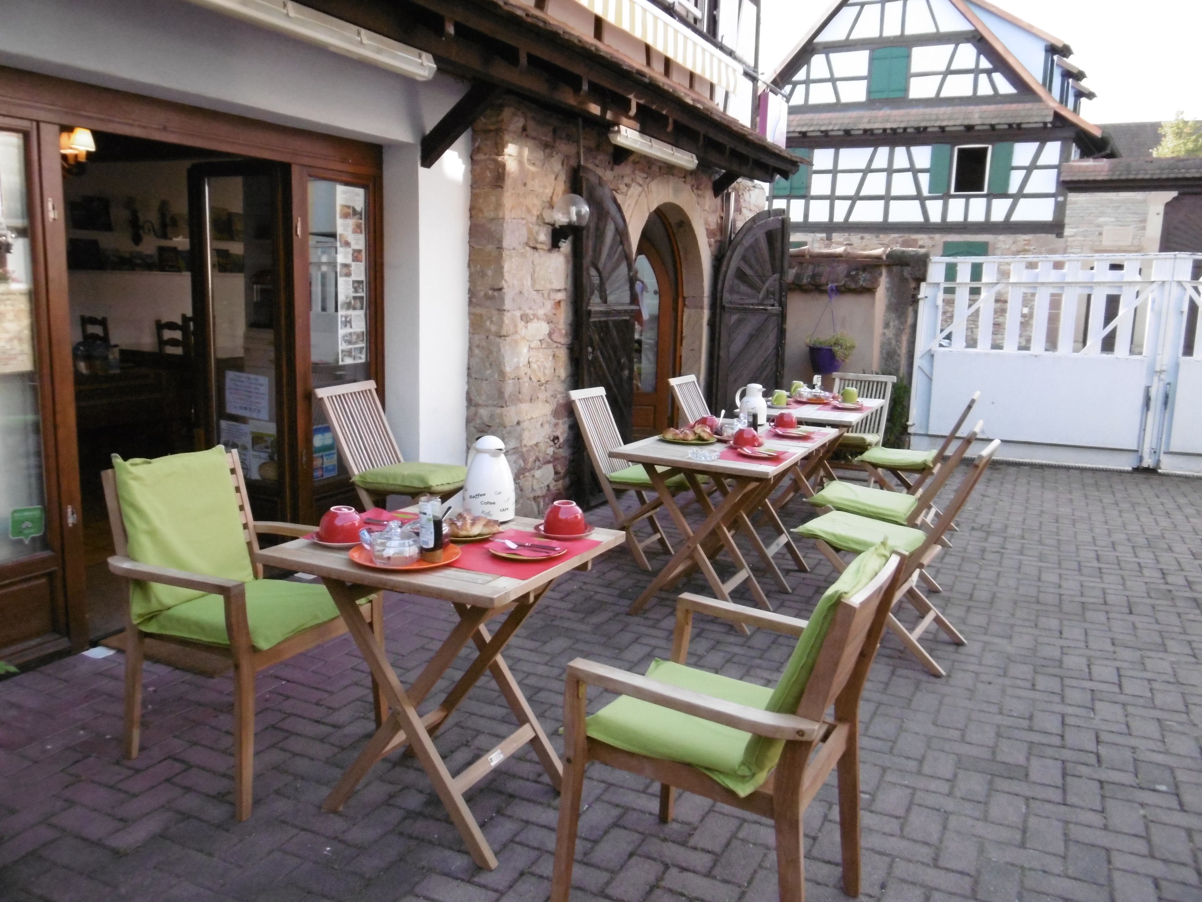 Ein Straßencafé mit Holztischen und -stühlen, Steinwänden und traditioneller europäischer Architektur.