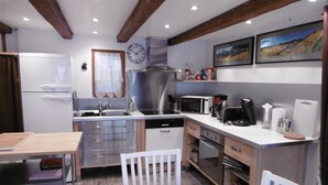 Una cocina moderna con electrodomésticos de acero inoxidable, un comedor con mesa y sillas, y un reloj en la pared.