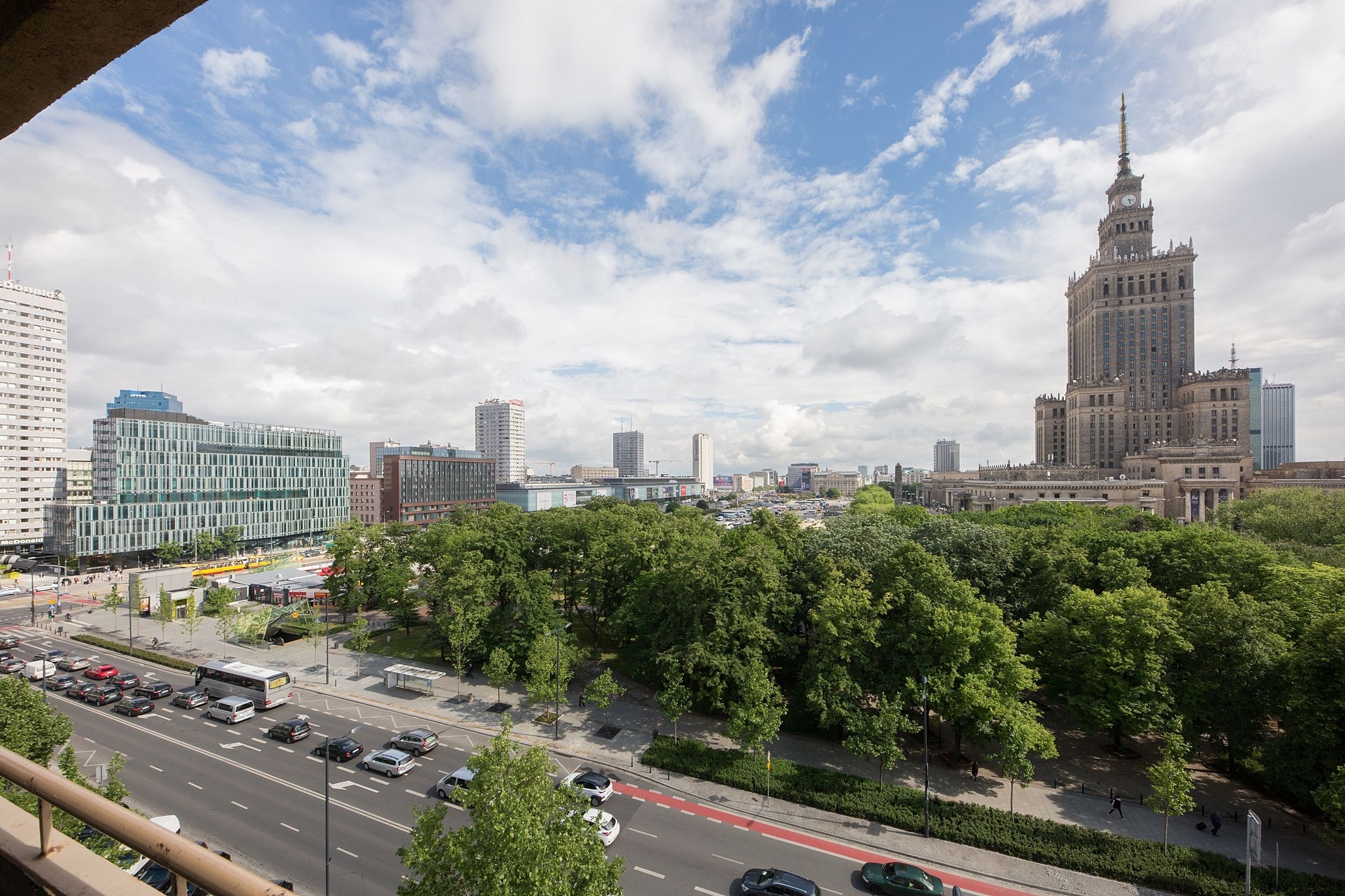 A cityscape with a prominent historical building, modern high-rises, and a green park area.