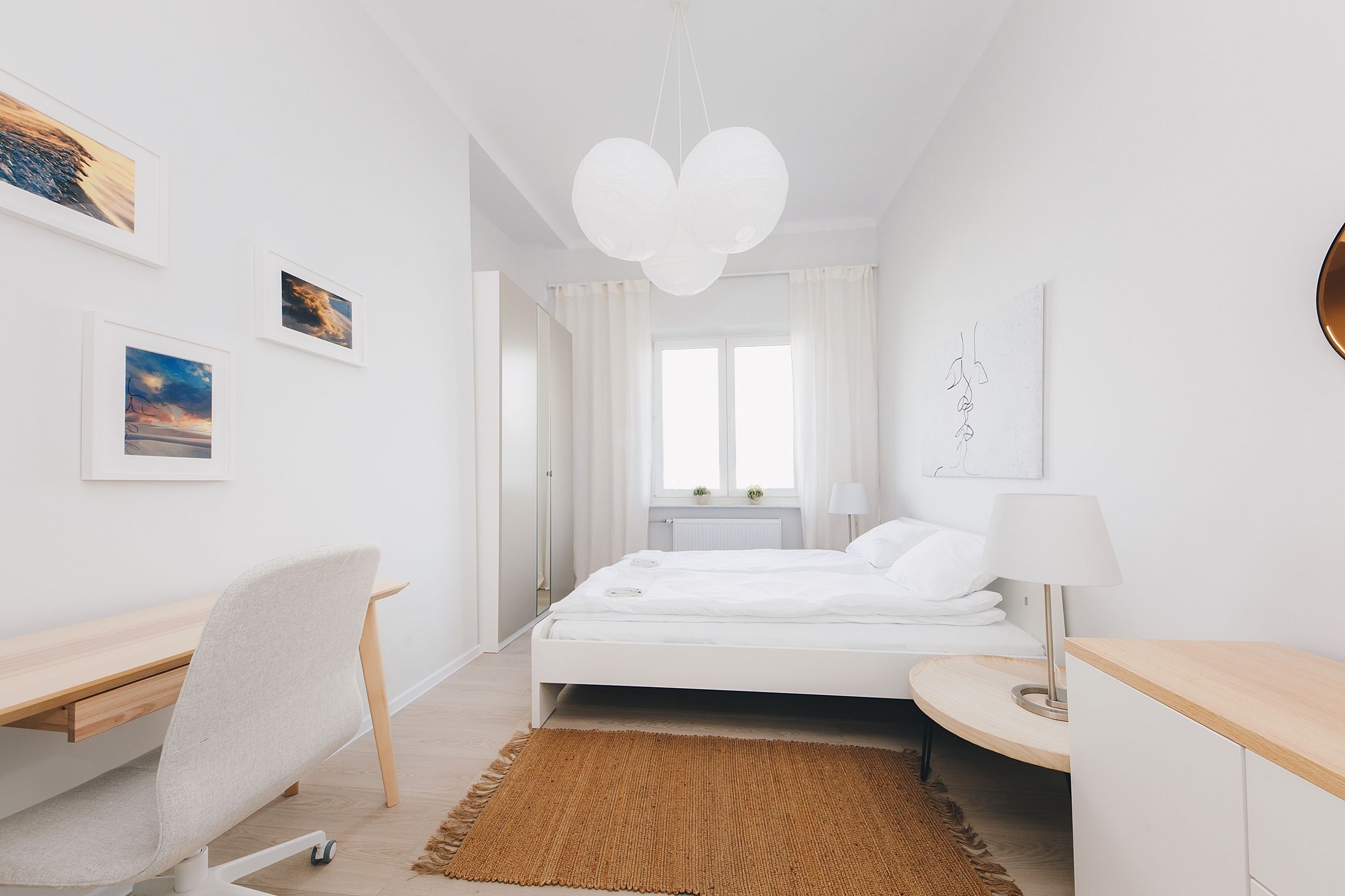 A modern bedroom with a bed, desk, chair, and artwork on the walls.