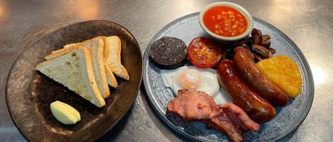 A breakfast plate with toast, eggs, sausages, bacon, tomatoes, and beans.