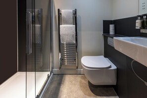 A modern bathroom with a glass shower enclosure, a towel rack, a toilet, and a sink. - The Royal Station Hotel (Carnforth)