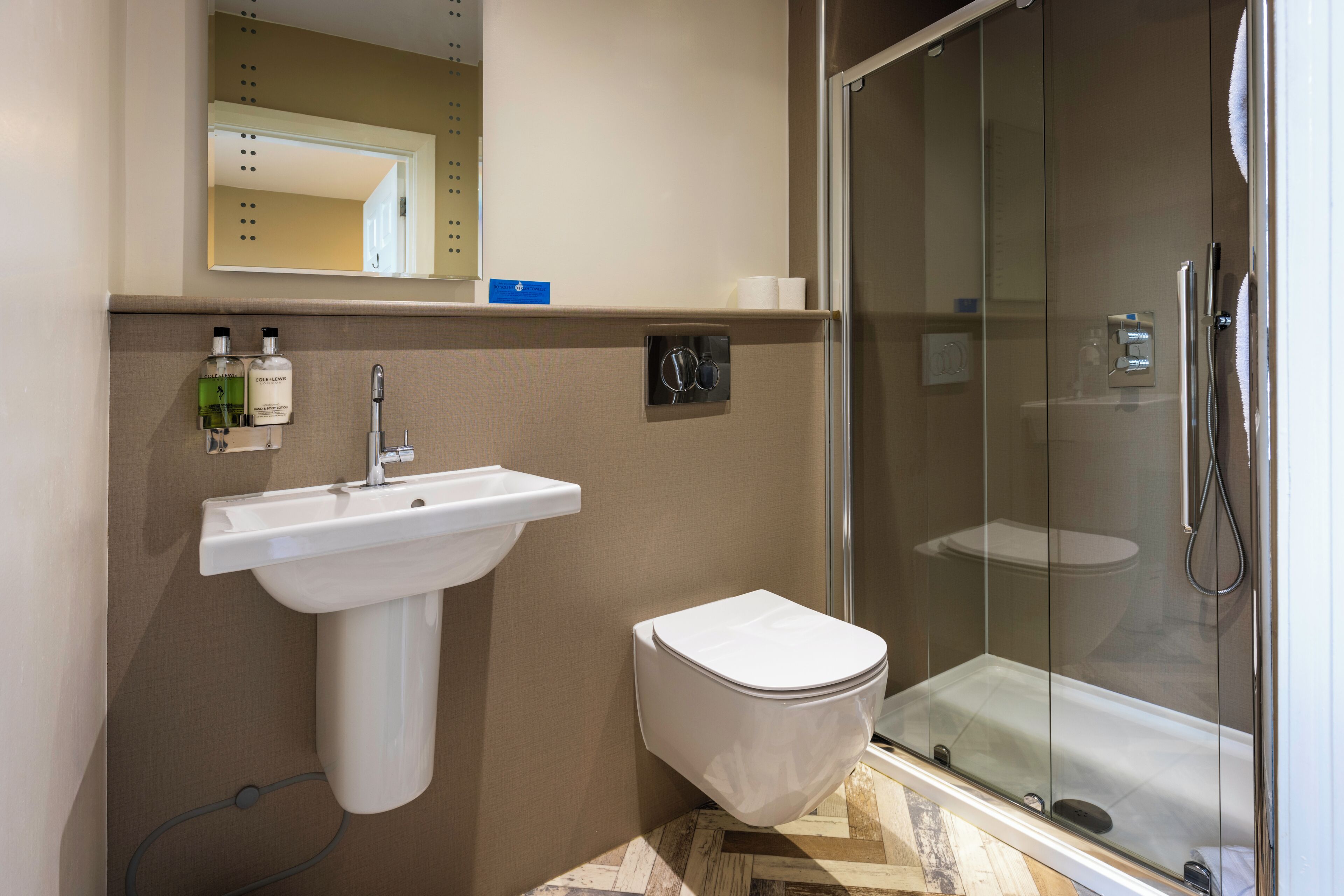 Une salle de bain équipée d’un lavabo, de toilettes et d’une douche à parois de verre.