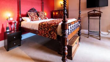 Un lit à baldaquin avec un cadre en bois, une table de chevet avec des tiroirs, une commode et un téléviseur fixé au mur.