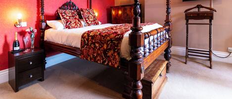 A four-poster bed with a wooden frame, a nightstand with drawers, a dresser, and a television mounted on the wall.