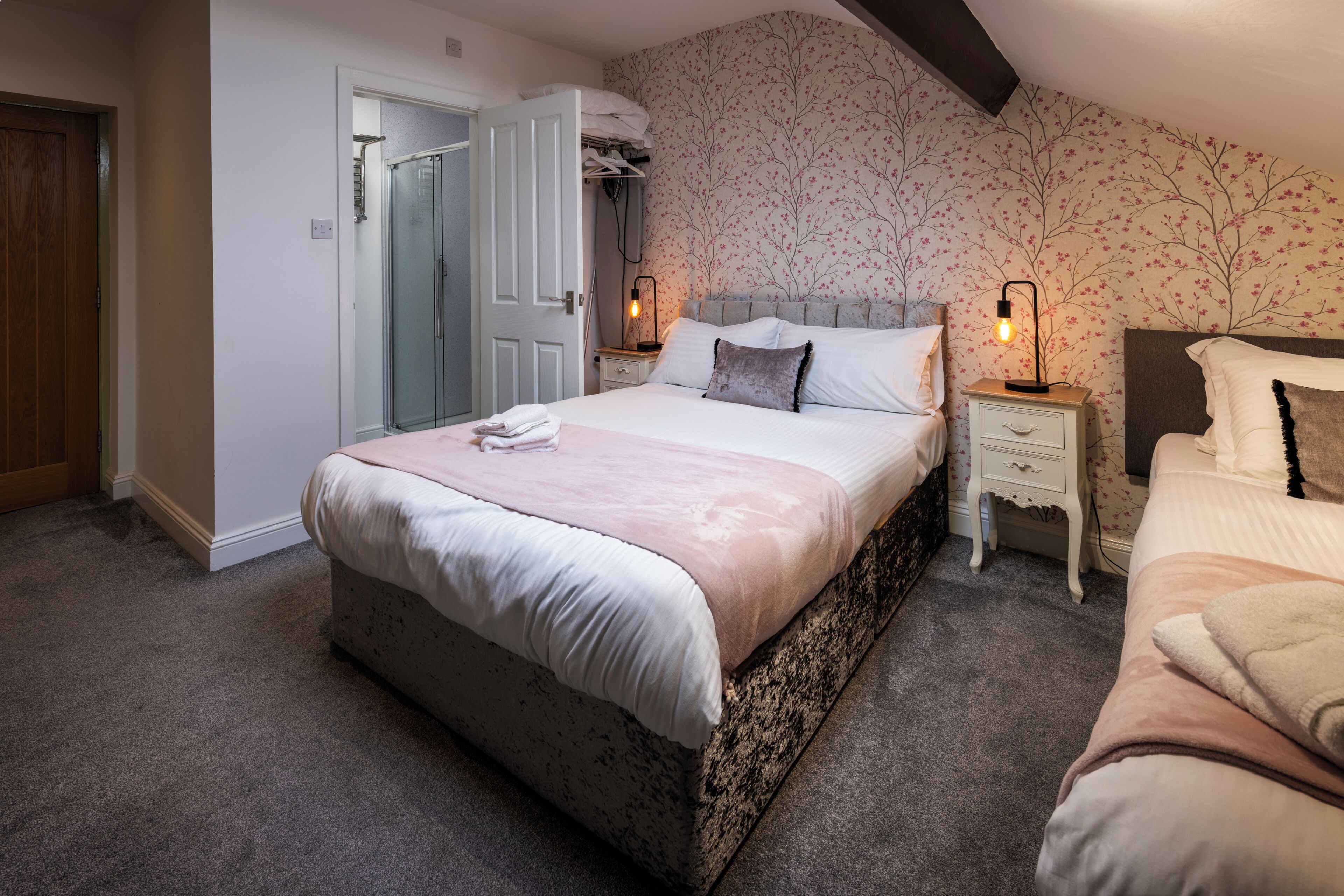 Une chambre à coucher avec un grand lit, une table de chevet avec une lampe, une commode et un placard dont la porte est ouverte.