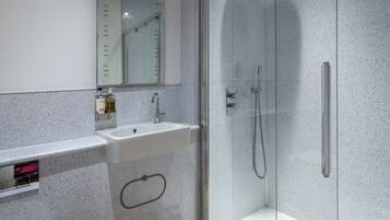 A modern bathroom with a glass-enclosed shower, a white sink, and a mirror above the sink.