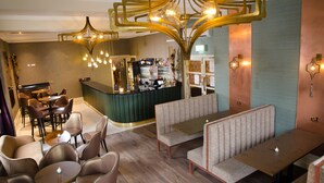 A bar area with a counter, seating, and a chandelier.